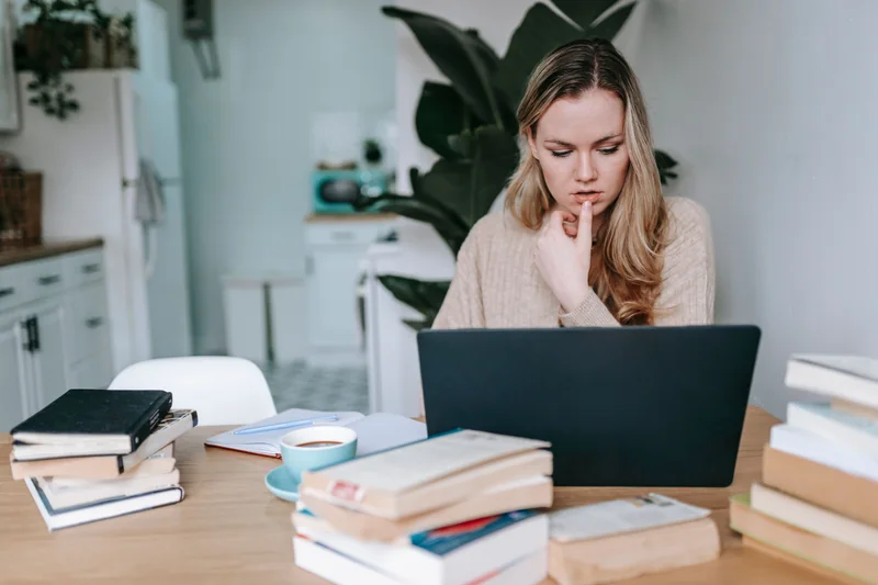 Adult learner studying at home with books and a laptop