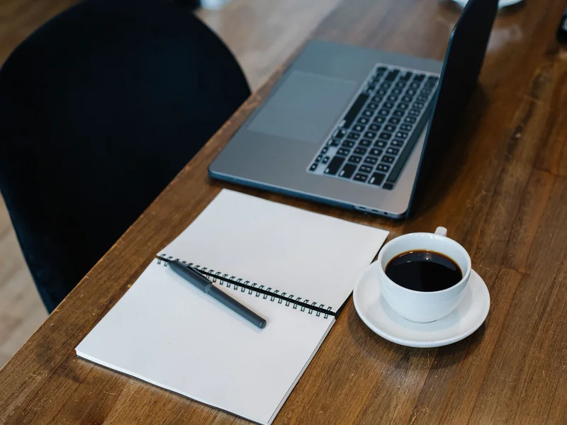 Notebook, laptop and coffee arranged for a daily study routine